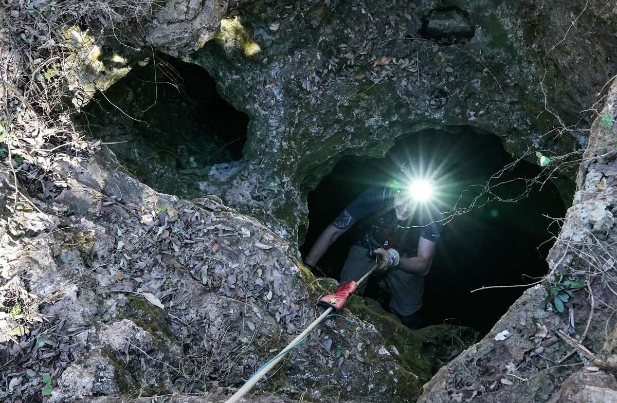 A volunteer climbs out of a Comal County cave over the Edwards Aquifer recharge zone during a Sunday project to remove trash from it.
