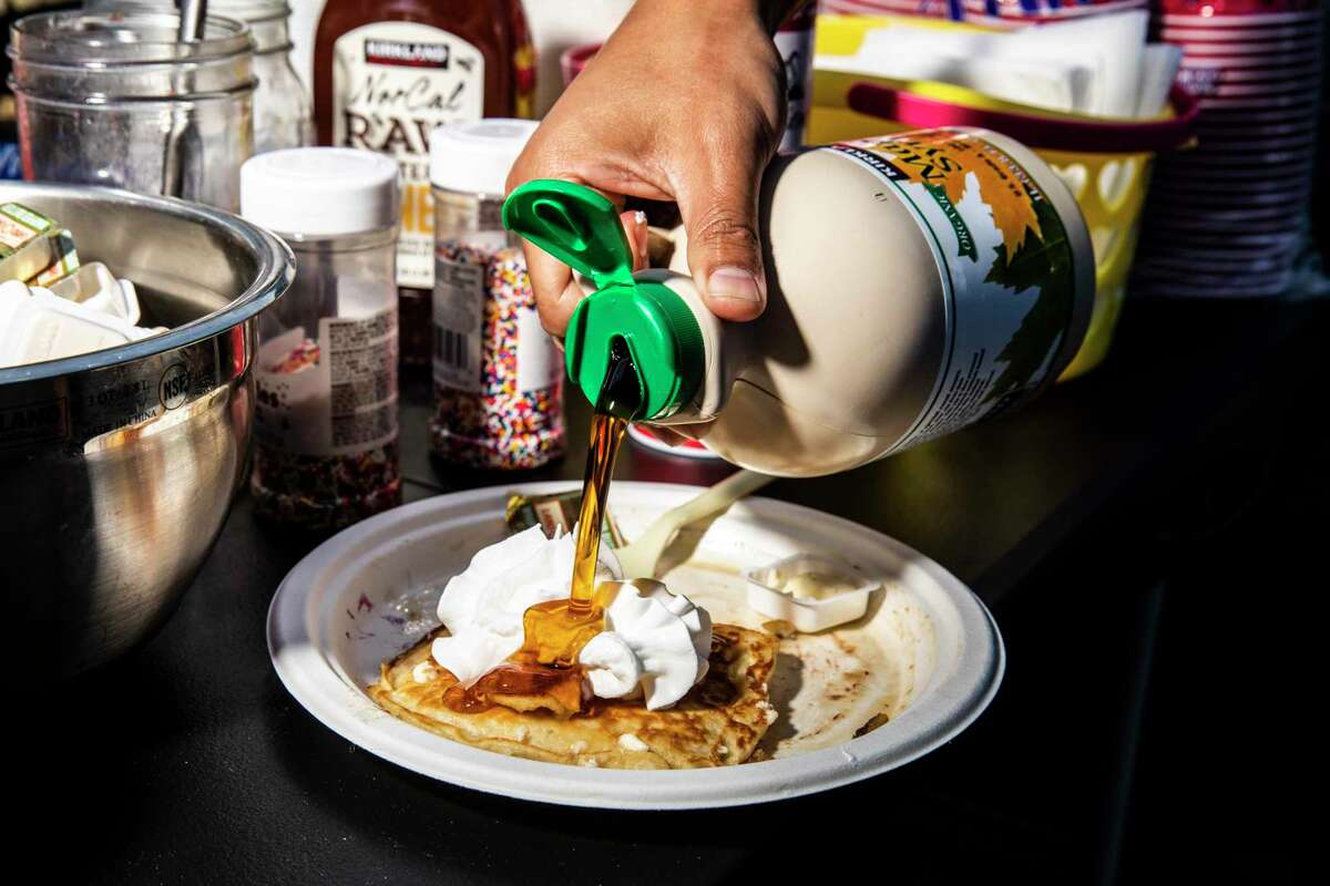 Chris Kane of San Diego pours maple syrup onto a plate of pancakes during a pancake party organized by Curtis Kimball in the Bernal Heights neighborhood of San Francisco.