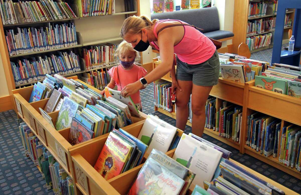 Last June, Rosalynn De-Hoogh, 4, looks for a book in the children's library with help from her mom, Melanie. Masks will continue to be required for all people in the library even as the town loosens its rules.