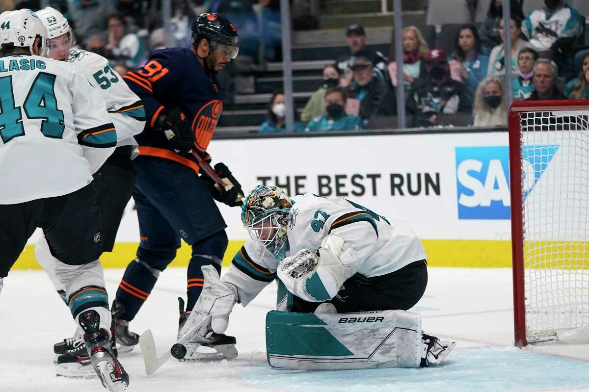 San Jose Sharks goaltender James Reimer reaches for the puck under Edmonton’s Evander Kane — a former Shark — during the second period of Monday’s game at SAP Center.