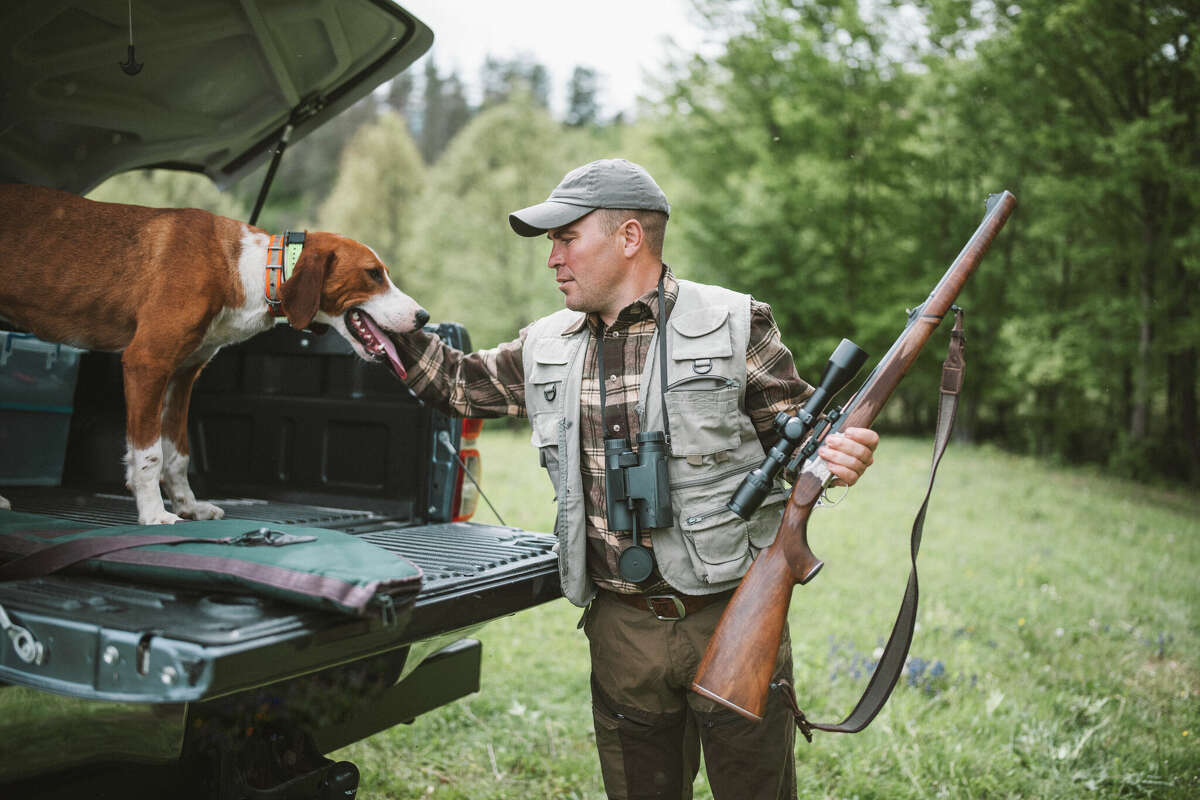 A shot of a hunter with rifle and his dog preparing for a hunt.