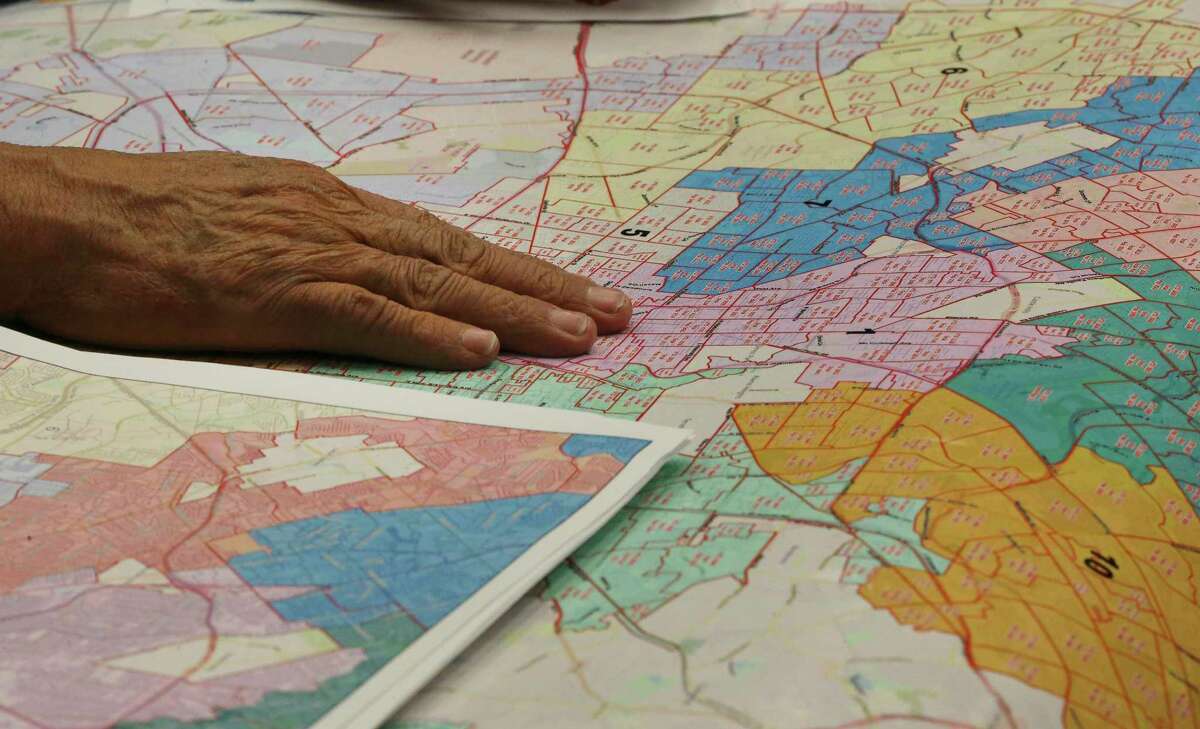 John Ybanez places his hand on a map of the city that outlines the council districts during the city's Re-districting Advisory Committee holds a meeting on Feb. 14.