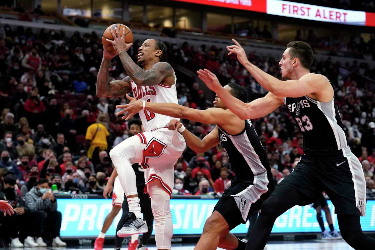 The Bulls’ DeMar DeRozan, left, drives past the Spurs’ Keldon Johnson, center, and Zach Collins during the second half Monday, Feb. 14, 2022, in Chicago. The Bulls won 120-109.