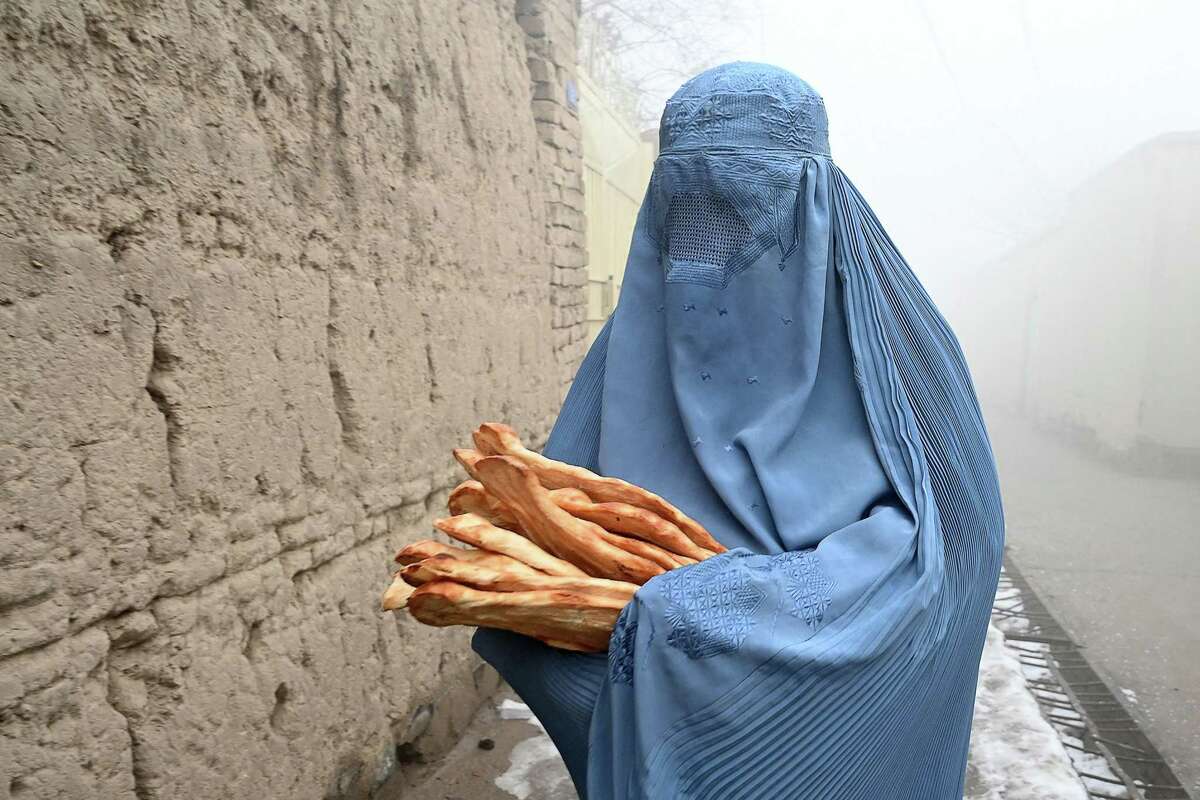 A woman wearing a burqa walks along a road towards her home after receiving free bread distributed as part of the Save Afghans From Hunger campaign in Kabul on Jan. 18, 2022. (Wakil Kohsar/AFP via Getty Images/TNS)