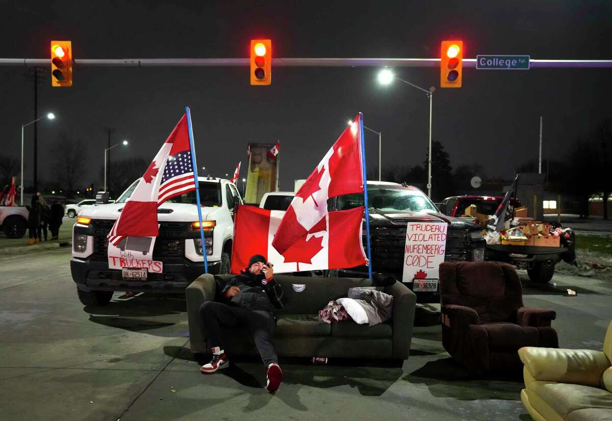 A trucker supporter sits on a couch as they block the access leading from the Ambassador Bridge, linking Detroit and Windsor, as truckers and their supporters continue to protest against the COVID-19 vaccine mandates and restrictions in Windsor, Ontario, on Feb. 9.