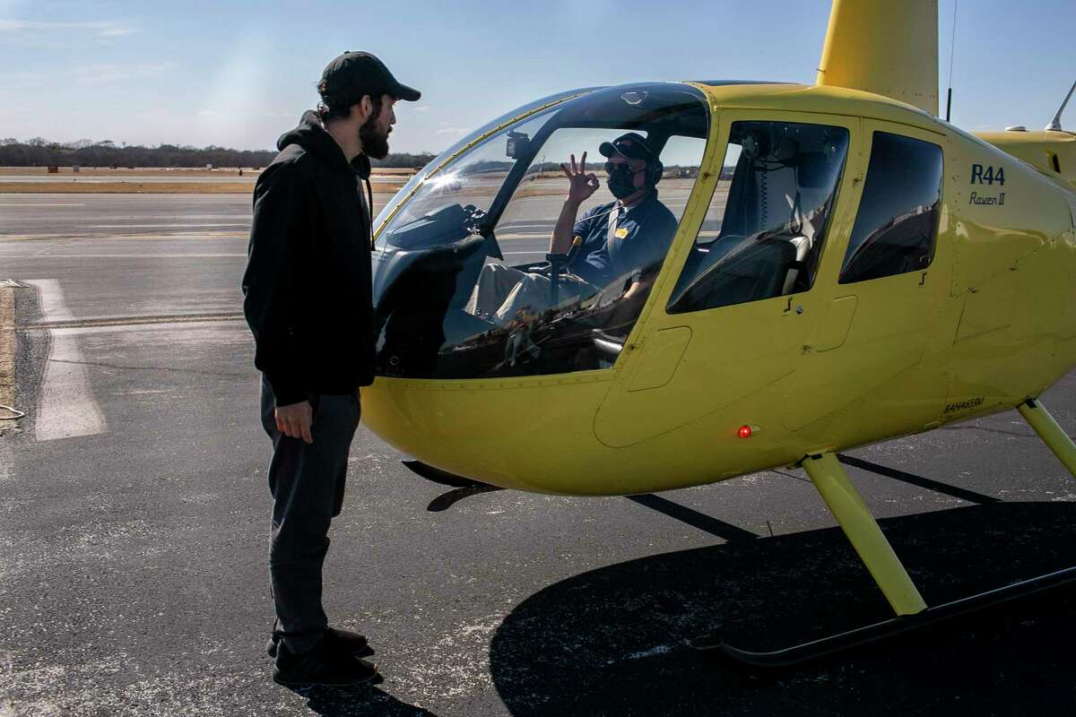 Alamo Helicopters owner and pilot Jose Corona signals to Josh Patino as he prepares to take off. Business is improving, “but it’s not 100 percent yet,” Corona says of the pandemic drop-off.