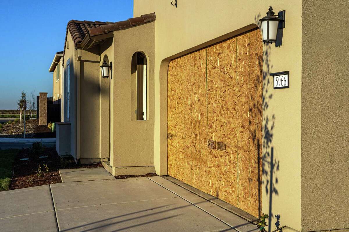Plywood is used to seal the garage of a new home in Sacramento, Calif., on Feb. 8, 2022. The home-building industry is having the most difficult time in decades meeting demand, the sum of many pandemic complications. But this moment reaches peak absurdity with garage doors. (Andri Tambunan/The New York Times)