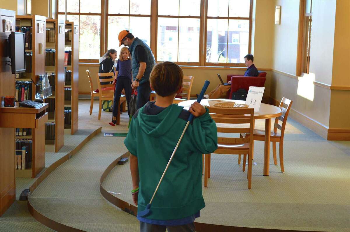 A player waits for his family to finish the hole at the Darien Library's annual Mini Golf event on Nov. 19, 2016.