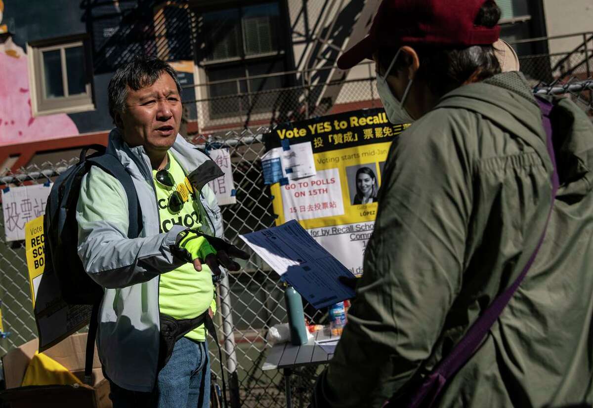 Kit Lam, a supporter of the school board recall and father of two who attend school at the San Francisco Unified School District, speaks to a voter while canvassing in Chinatown on election day in San Francisco, California Tuesday, Feb. 15, 2022.