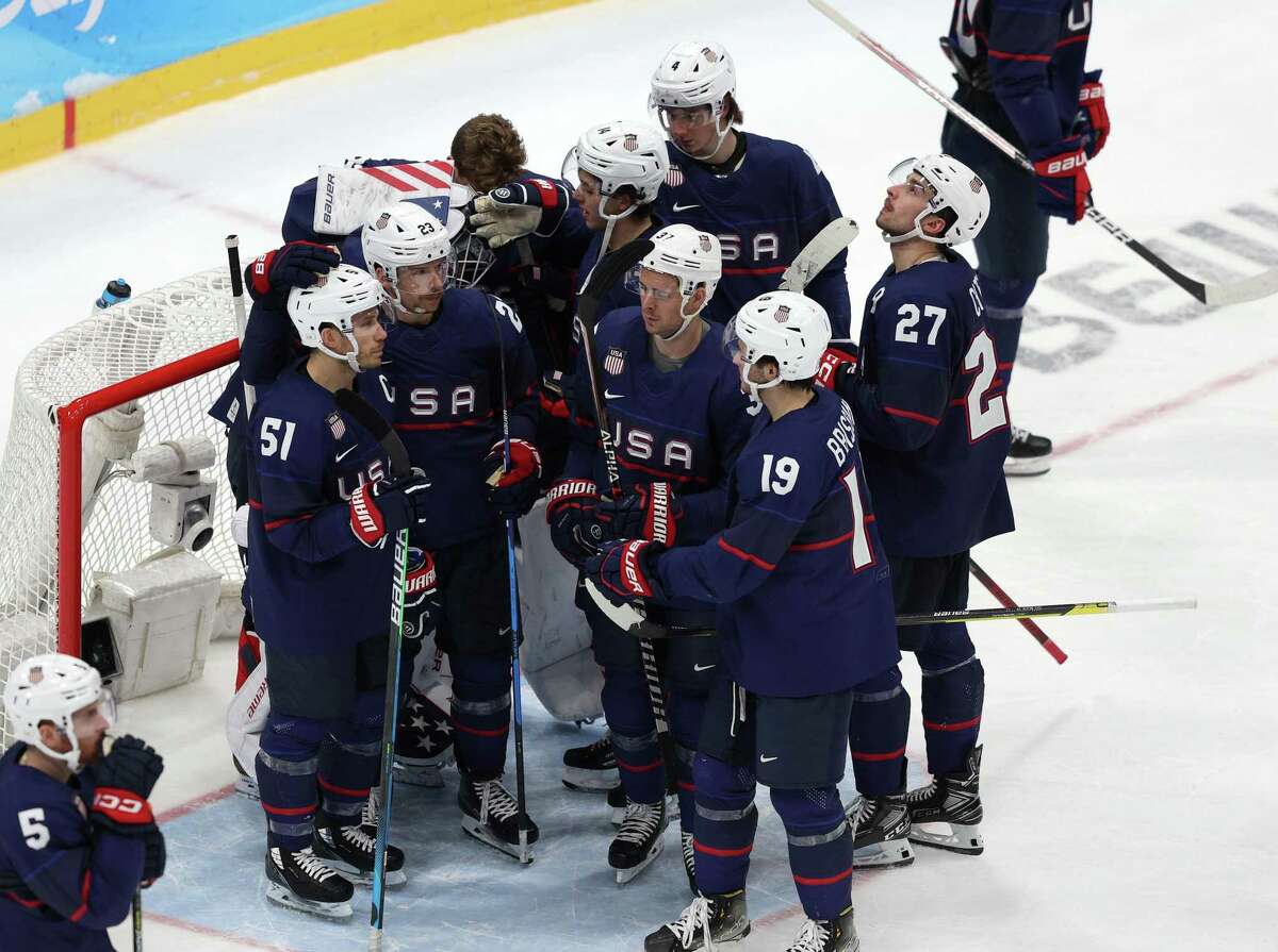 Team United States players gather together around goaltender Strauss Mann after their shootout loss to Slovakia.