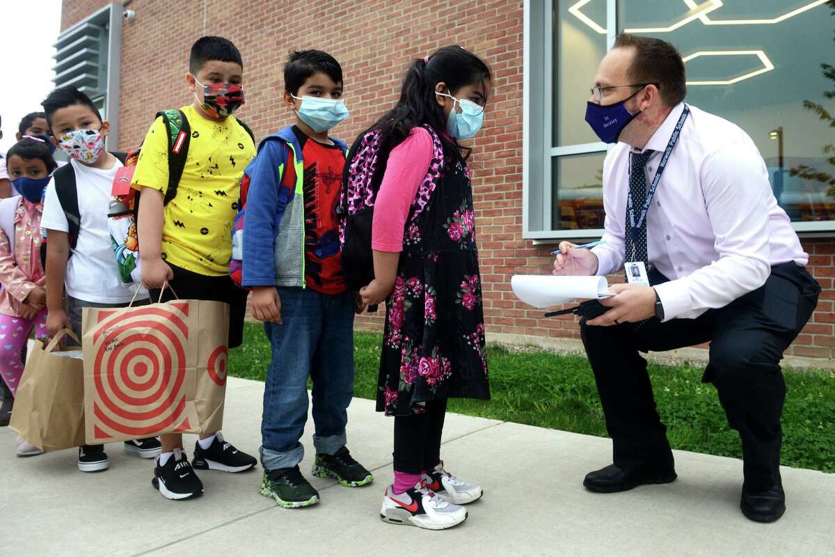 Techer Jeffrey Beckley greets students as they arrive for the first day of class at Jefferson Elementary School, on the Ponus Ridge STEAM Academy campus in Norwalk, Conn. Aug. 30, 2021.