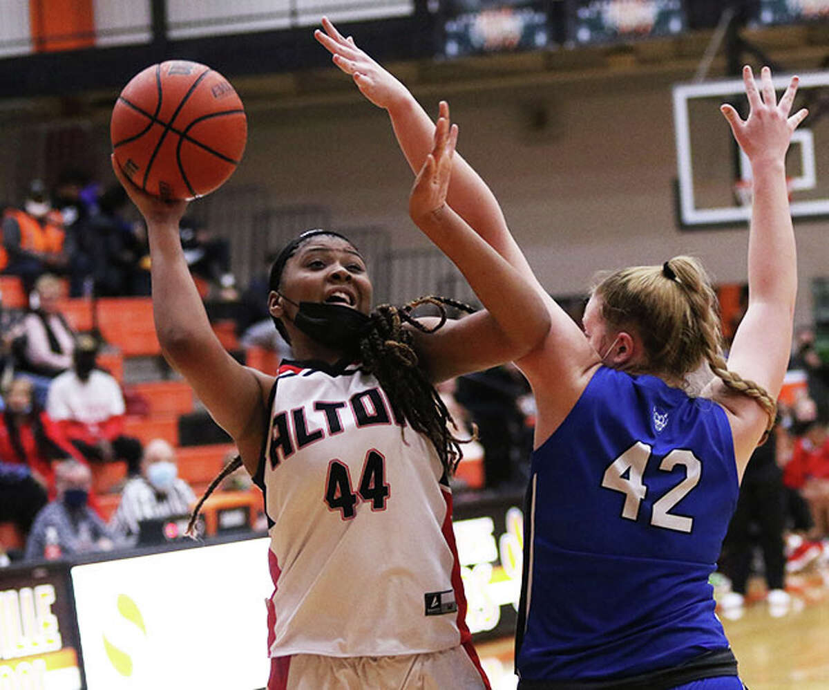 Alton's Jarius Powers (44) scores over Quincy's Taylor Fohey for two of her 21 points in the Redbirds' semifinal victory in the Edwardsville Class 4A Regional at Lucco-Jackson Gym. 