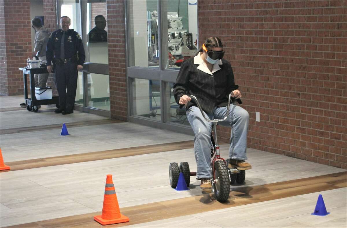 Trooper Todd Goodrich of the Michigan State Police oversees the alcohol impairment simulation goggles demonstration during an event by criminal justice students from the West Shore Educational Service District Career and Technical Education Center.