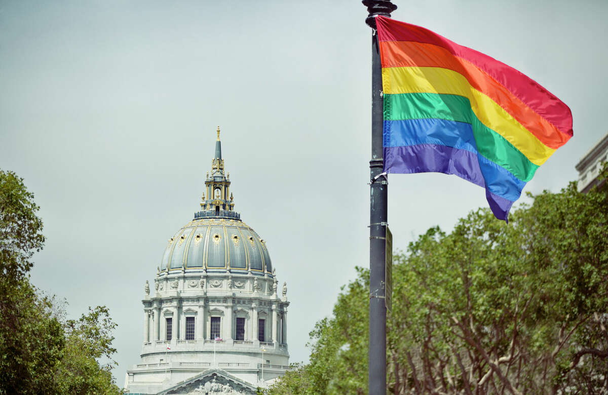 A rainbow flag waves in front of San Francisco City Hall.
