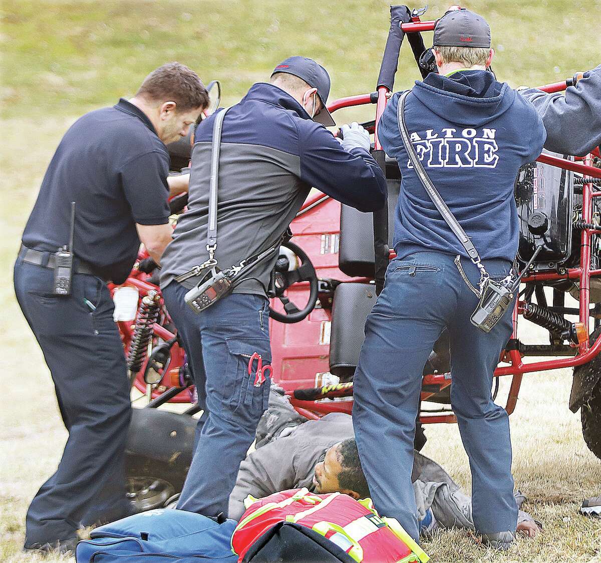 John Badman|The Telegraph Alton firefighters push a four-wheeler back onto its wheels to free the man Wednesday in Norside Park.
