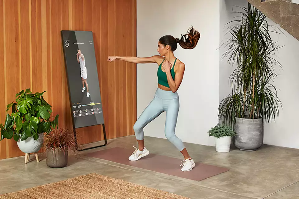 A woman exercising at home in front of an interactive Lululemon smart fitness mirror, representing computer vision and machine learning technology in retail