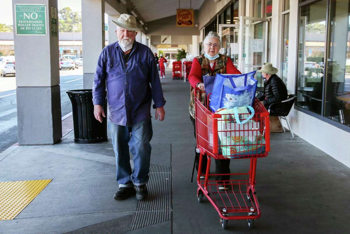 (From left to right) Tom and Faye Hendricks walk past Trader Joe's to their car on Wednesday, Feb. 16, 2022, in San Rafael, Calif.