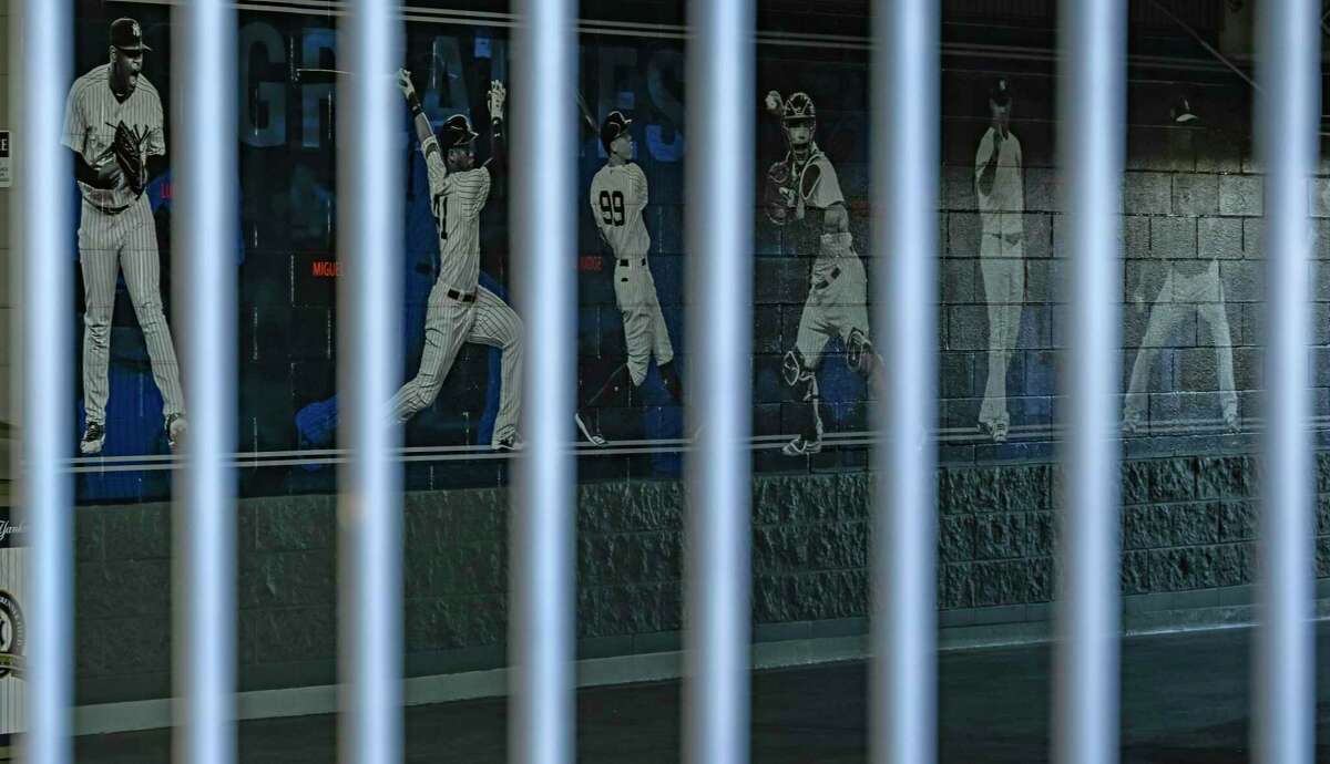 A mural of players adorns a wall behind a locked gate on the day pitchers and catcher were scheduled to report to camp at the New York Yankees spring training complex at George M. Steinbrenner Field Wednesday, Feb. 16, 2022, in Tampa, Fla. The usual spring training buzz is missing because of a lockout that’s now extended to 76 days and become the second-longest work stoppage in baseball history. (AP Photo/Steve Nesius)