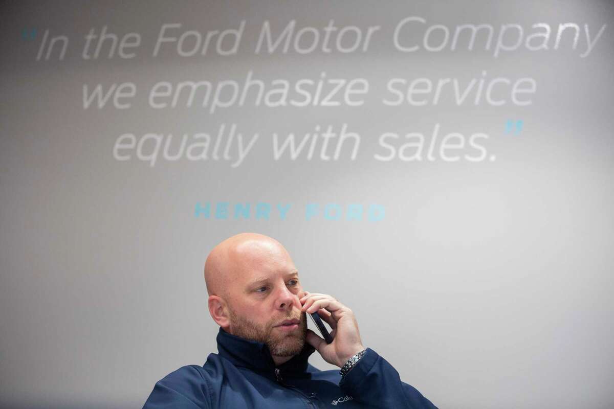 Car sales specialist David Claar talks to a customer who is interested to trade in his car and buy a new vehicle Thursday, Jan. 20, 2022, at Doggett Ford in Houston. Claar said he works with customers over the phone and on the computer most of the time. He kept a spreadsheet of customers and their desired vehicles, and he would notify them if something comes up at the dealership.