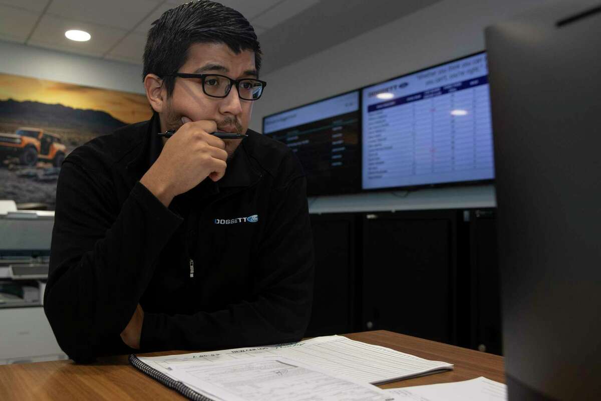 Car sales specialist Javier Medina Jr., left, works on details with sales manager Victor Ruvalcaba to help customer Pedro Gonzalez building a Super Duty F-350 Thursday, Jan. 20, 2022, at Doggett Ford in Houston. Gonzalez wanted to get a truck for his construction company as soon as possible, but Medina said the orders are backed for at least six months.