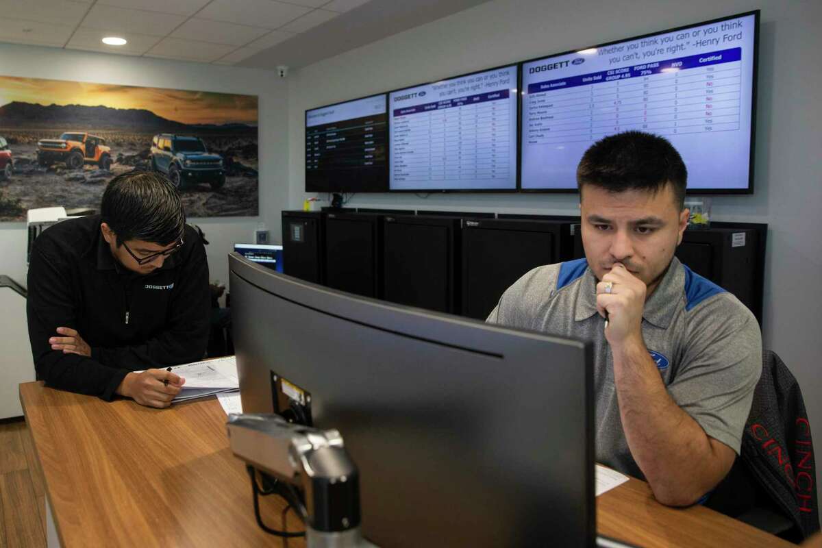 Car sales specialist Javier Medina Jr., left, works on details with sales manager Victor Ruvalcaba to help customer Pedro Gonzalez building a Super Duty F-350 Thursday, Jan. 20, 2022, at Doggett Ford in Houston. Gonzalez wanted to get a truck for his construction company as soon as possible, but Medina said the orders are backed for at least six months.
