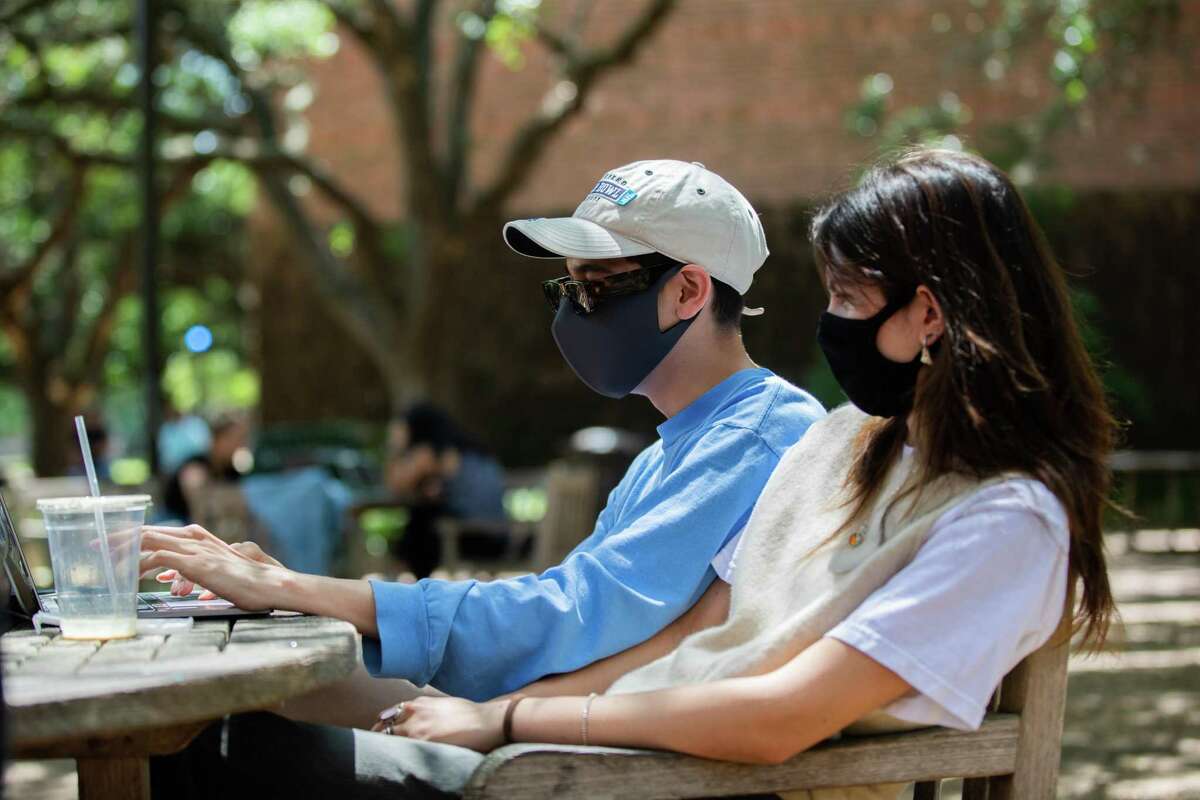 Rice University student Miguel Luna, 21, wears a protective mask at campus because of his proximity to Maya Chamberlain, 20, Monday, April 26, 2021, in Houston. Rice University no longer requires people to wear a mask outdoors.