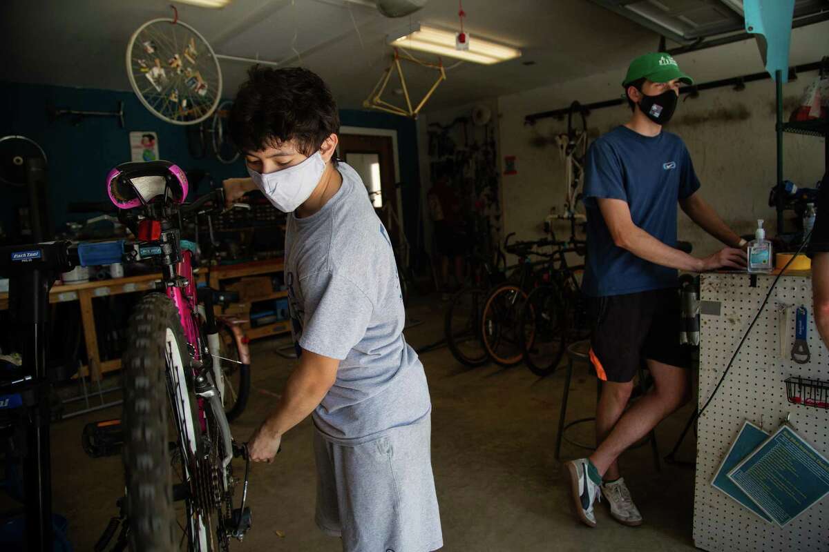Rice University Rice Bikes’ personnel manager and mechanic Diego Casanova, left, 20, works on a bicycle while wearing a mask, Monday, April 26, 2021, in Houston.