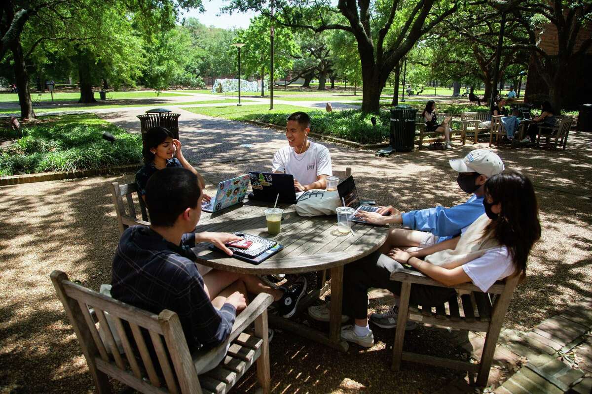 Rice University students share a table outdoors, some wearing a protective mask and others not, Monday, April 26, 2021, in Houston. An email from the university administration said that masks will not be required outdoors as long as people socially distance at least 3 feet and that those who are fully vaccinated can opt out of weekly testing.