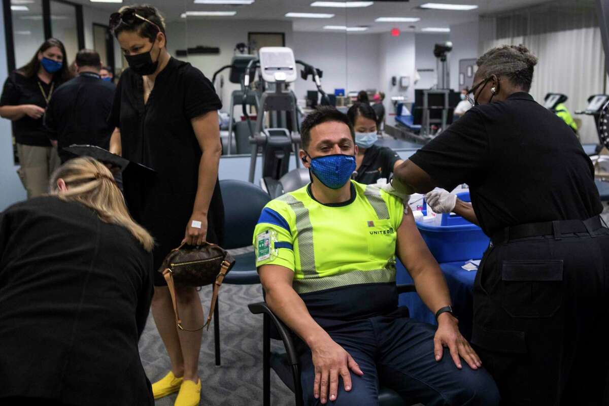 United Airlines employee Arnoldo Fernandez receives a Pfizer-BioNTech COVID-19 vaccine from Gladys McGinnis during a vaccine clinic at George Bush Intercontinental Airport Tuesday, April 27, 2021 in Houston. United Airlines has been vaccinating their IAH-based employees at the on-site airport employee clinic. United has now extended the invitation to vaccinate all airport workers and the airline's business partners.
