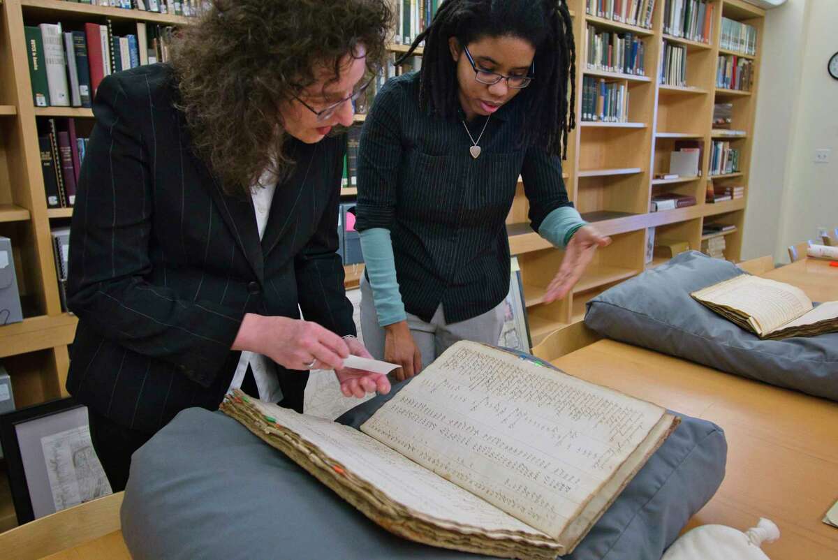 Historians with the Albany Institute of History and Art, Tricia Barbagallo, left, and Lacey Wilson, look through the 1799 assessment roll for the City of Albany on Tuesday, Feb. 15, 2022, in Albany, N.Y. Barbagallo is researching African American history in the City of Albany from 1600-1900. Wilson is researching African American history in the City of Albany in the 20th and 21st century.
