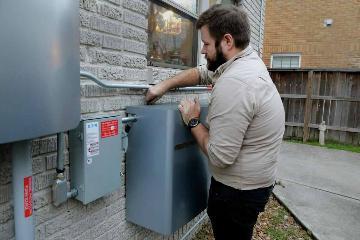 Sam Bryan removes the battery panel covers in the back yard of the new solar panel power system he installed on the roof his two story 1930’s home Tuesday, Feb. 1, 2022 in Houston, TX.