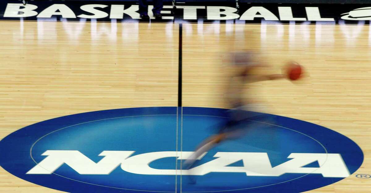 FILE - A player runs across the NCAA logo during practice in Pittsburgh before an NCAA tournament college basketball game, March 14, 2012. NCAA enforcement has inquired about how college athletes are earning money off their names, images and likenesses at multiple schools as it attempts to police activities that are ungoverned by detailed and uniform rules. NCAA Vice President of Enforcement Jon Duncan told the Associated Press that letters of inquiry have gone out over the last few months. (AP Photo/Keith Srakocic, File)