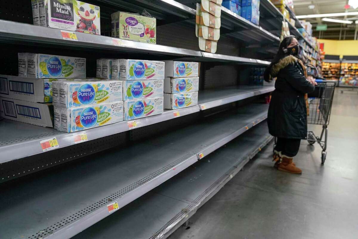 A woman looks over shelves, some of which are empty, at a Walmart store in Teterboro, N.J., on Jan. 12, 2022.