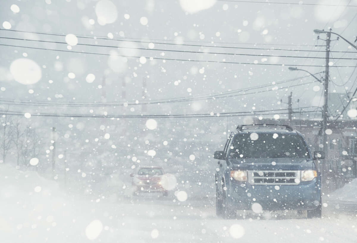 FILE - Motorists navigate a city street in white out conditions.