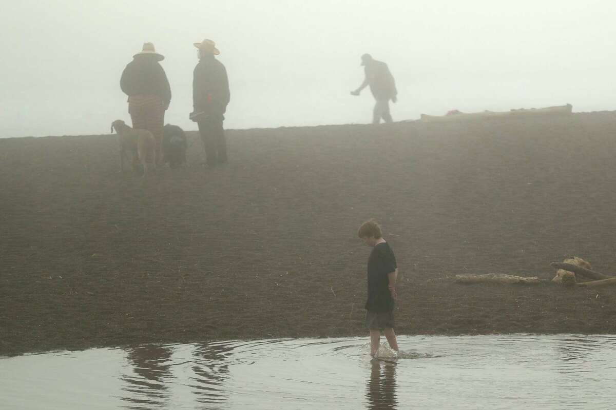 Heavy fog enshrouds beachgoers at Rodeo Beach in Sausalito, Calif. A slow-moving weather system will travel from the North Bay to the South Bay, bringing light, spotty showers, hail and evening lightning across the region.