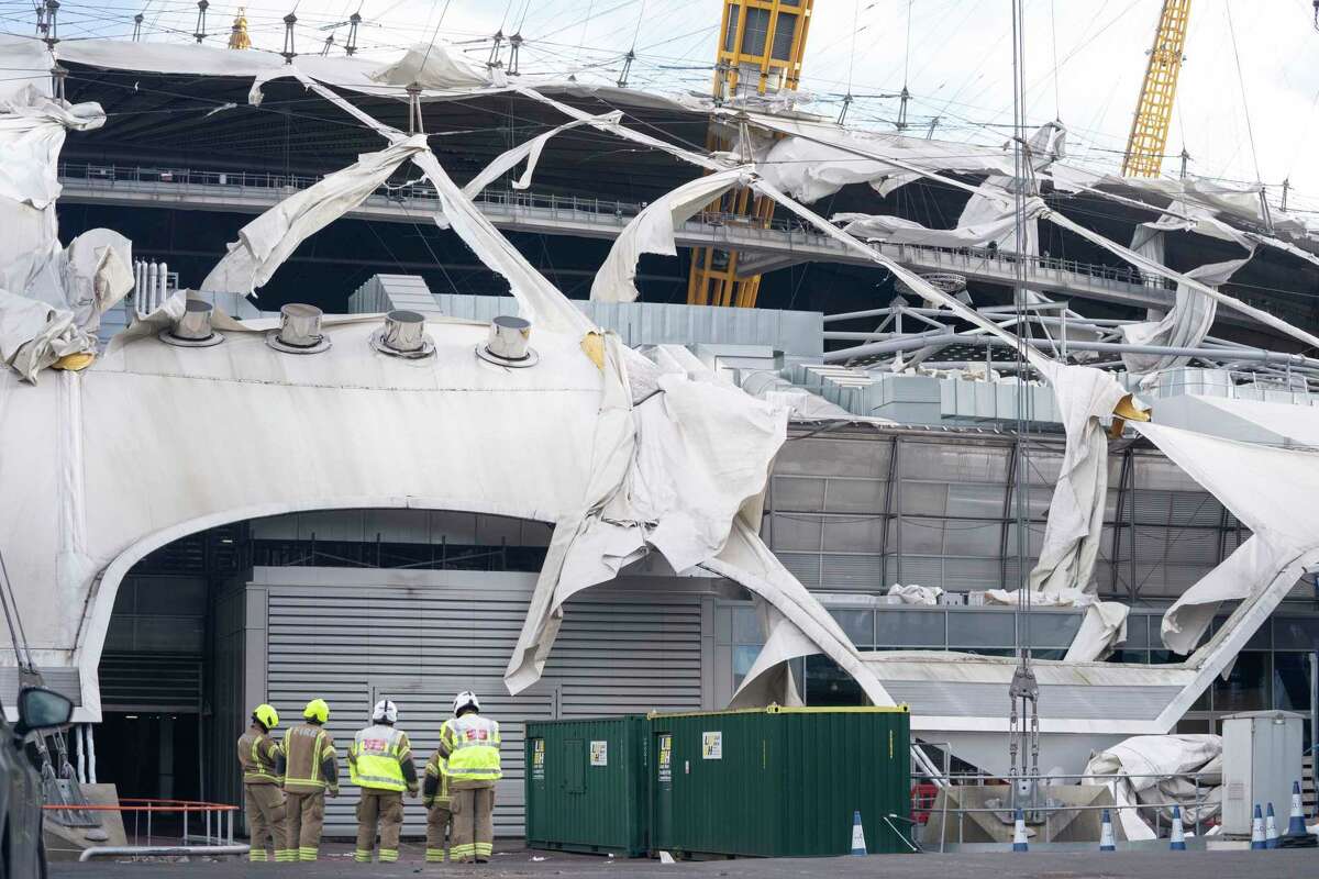 Firefighters inspect damage to the roof of the O2 Arena, caused by Storm Eunice, in south east London, Friday, Feb. 18, 2022. London Fire Brigade said that there were no reports of any injuries as around 1,000 people were evacuated from the building, formerly known as the Millennium Dome, which hosts major events including concerts and features restaurants, bars, shops and a cinema. Millions of Britons were urged to cancel travel plans and stay indoors Friday amid fears of high winds and flying debris as the second major storm in the week prompted a rare "red" weather warning across southern England. (Stefan Rousseau/PA via AP)