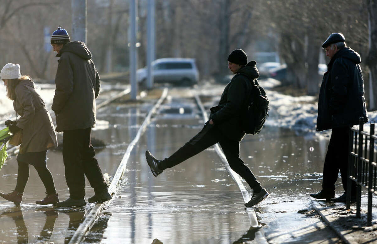 People overstep water in a flooded street. (Photo by Yevgeny Sofiychuk\TASS via Getty Images)