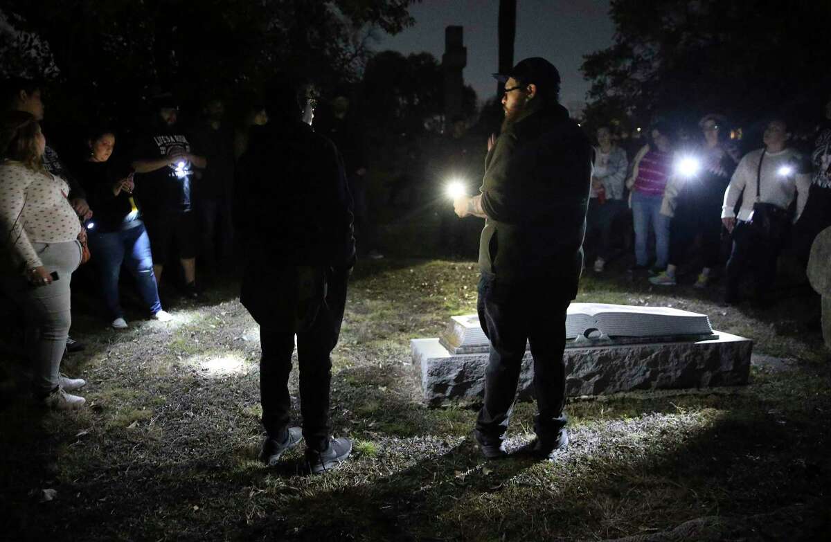 Fred (right) and Stephen Garza-Guzman of Curious Twins Paranormal stand over a grave site as they lead a tour of City Cemetery No. 1. The tour includes explanations of gravestone symbols.
