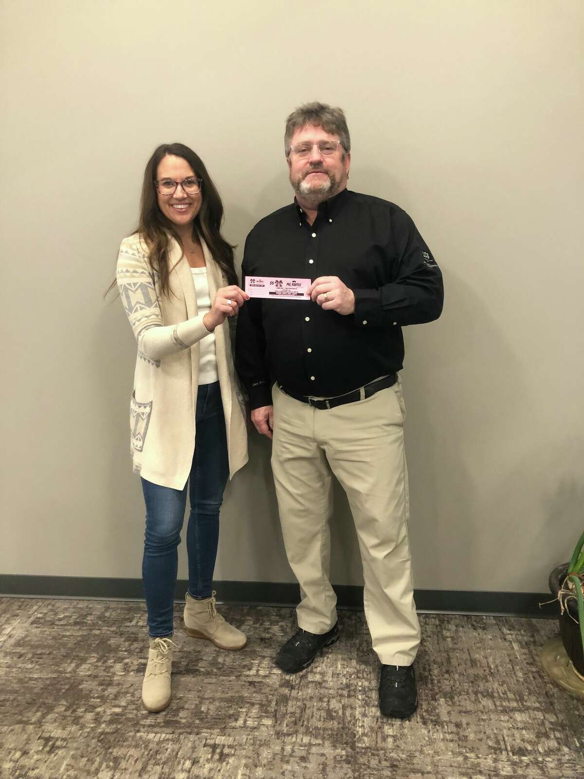 Stacie Bytwork, the President of the Manistee Area Chamber of Commerce purchases a “Pig Raffle” ticket from 350 Club President, Mark Sandstedt. 