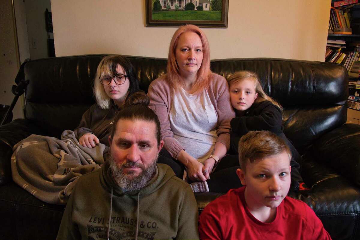 Rebekah Hogan, center, and her husband, James Hogan, foreground left, with their children, Caleigh, 15, background left, Sebastian, 9, background right, and Ben, 13, foreground right, at their home on Thursday, Feb. 17, 2022, in Latham, N.Y. Every member of the family is suffering from lingering symptoms from having COVID-19 in the fall of 2020.