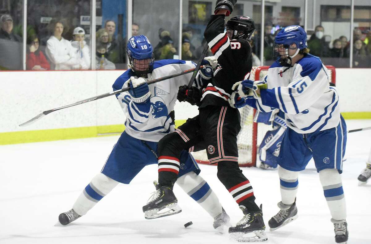 Darien's Graf Ely (10) and Billy Branca (15) battle New Canaan's Bryce Lyden (16) during a boys ice hockey game at the Darien Ice House on Saturday, Feb. 12, 2022.