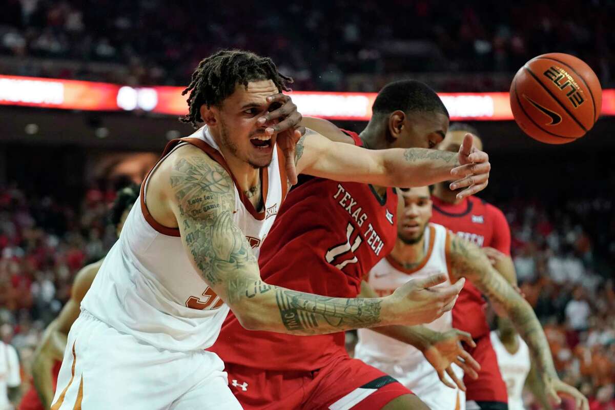 Texas forward Christian Bishop, left, and Texas Tech forward Bryson Williams (11) scramble for a loose ball during the second half of an NCAA college basketball game, Saturday, Feb. 19, 2022, in Austin, Texas. (AP Photo/Eric Gay)