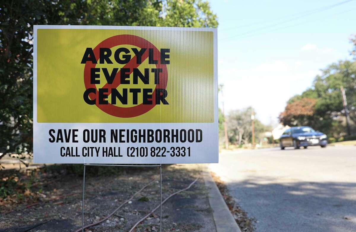 A vehicle drives along Patterson Avenue where road signs object to planned construction at the Argyle Club in Alamo Heights.