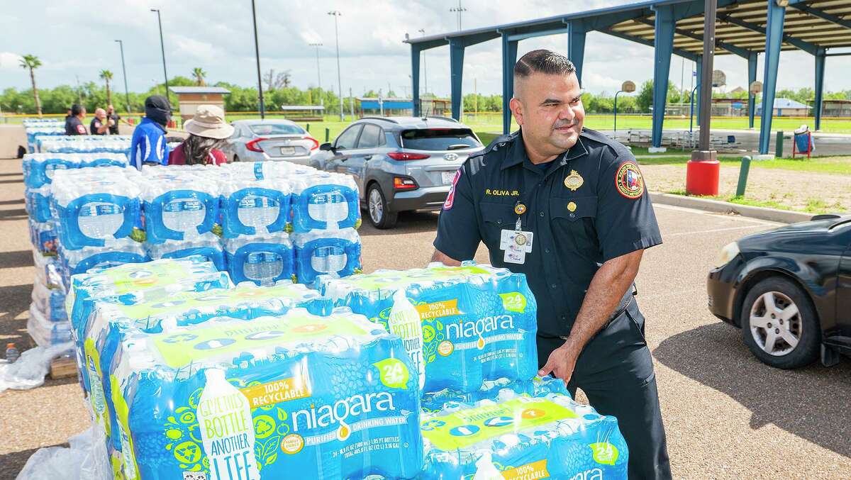 Laredo Firefighter Ricardo Oliva Jr. helps load cases of water onto vehicles during a water distribution at Slaughter Park, Friday, July 9, 2021, in response to the city wide boil water notice.