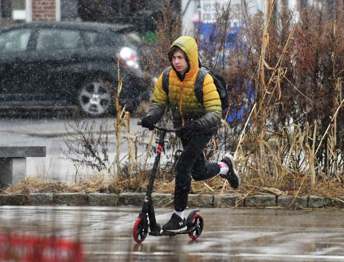 A boy rides his scooter through the snow in Old Greenwich, Conn. Thurday, Jan. 20, 2022.