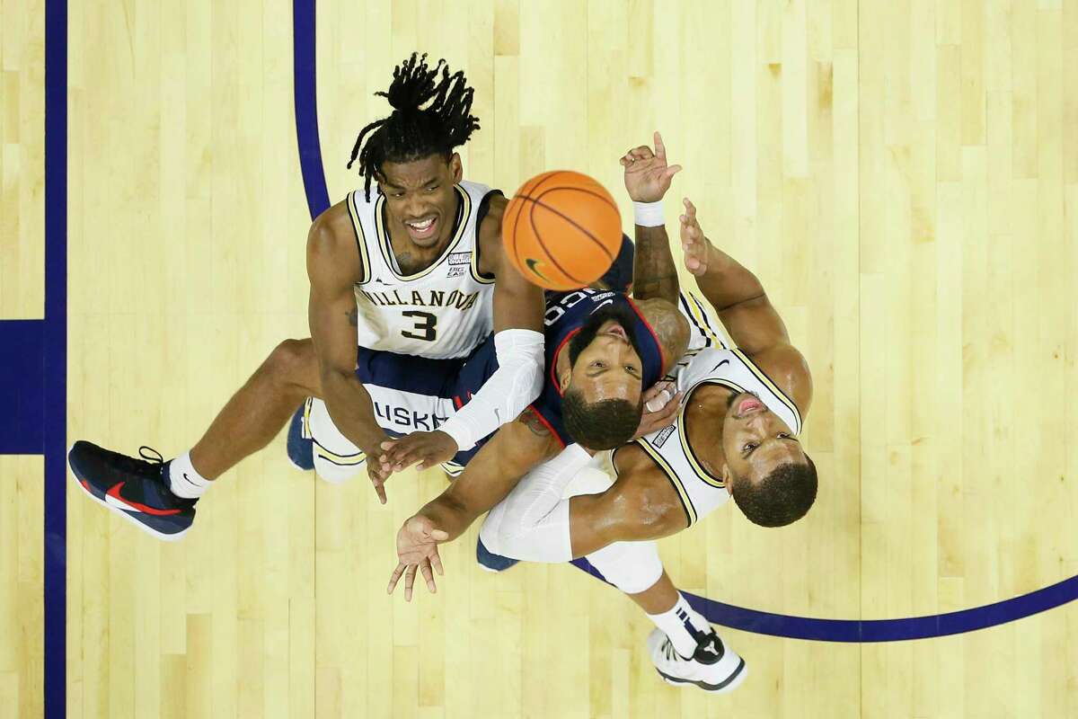 UConn’s R.J. Cole, center, takes a shot between Villanova's Brandon Slater (3) and Eric Dixon on Feb. 5 in Philadelphia. The Big East rivals meet for the second time this season on Tuesday.