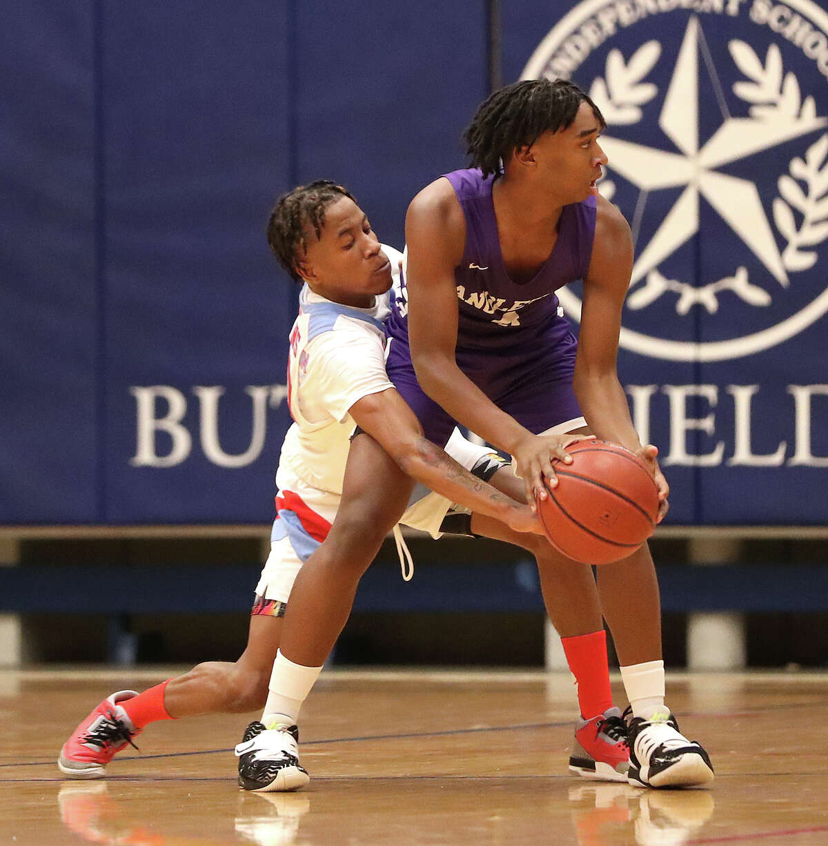 Angleton High School's Majestic Ford (0) battles against Madison High School's Gerald Harper (20) during the second half of a Region III-5A bi-district boys basketball playoff game at Butler Fieldhouse on Monday, Feb. 21, 2022 in Houston.