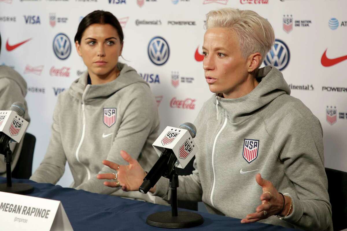 FILE - United States women's national soccer team members Alex Morgan, left, listens as teammate Megan Rapinoe speak to reporters during a news conference in New York, Friday, May 24, 2019. U.S. women soccer players reached a landmark agreement with the sport’s American governing body to end a six-year legal battle over equal pay, a deal in which they are promised $24 million plus bonuses that match those of the men. The U.S. Soccer Federation and the women announced a deal Tuesday, Feb. 22, 2022, that will have players split $22 million, about one-third of what they had sought in damages.