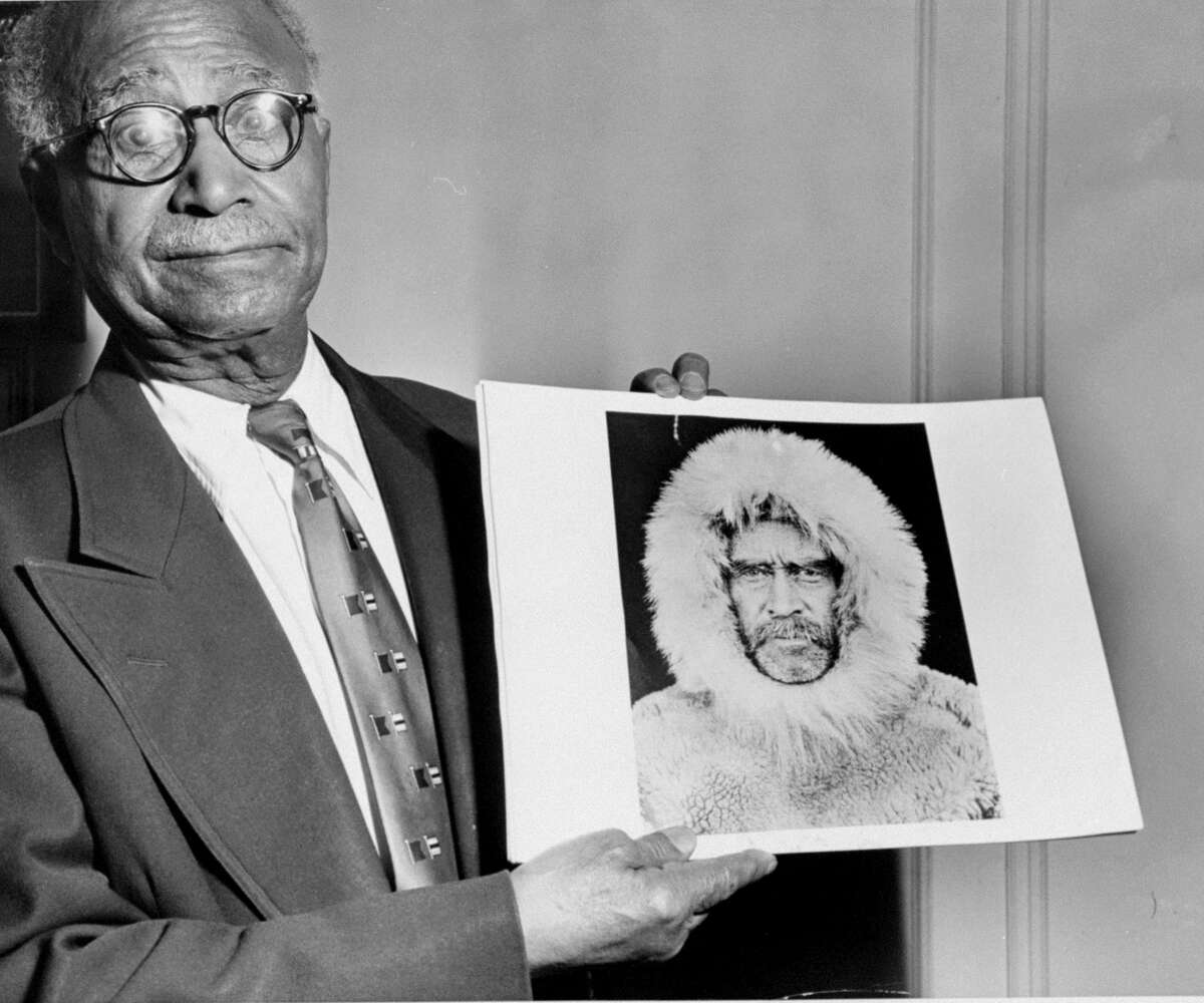Matthew Henson holds a picture of himself as he appeared when he was a member of Adimiral Perry's expedition to the North Pole. 