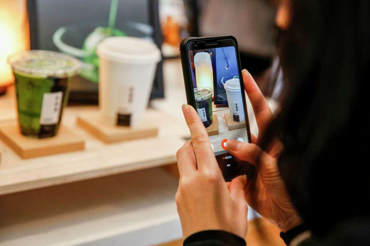Customer Victoria Jang takes a picture of her matcha latte at Three Tea Bowls.